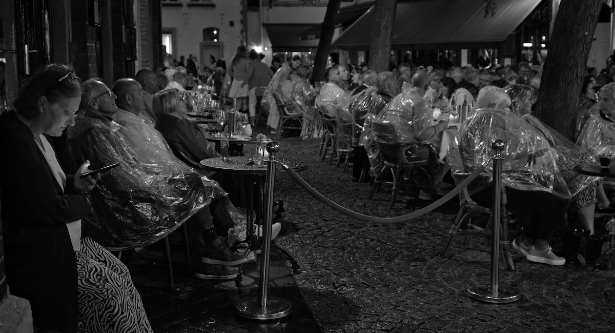 tourists sit outside in the rain